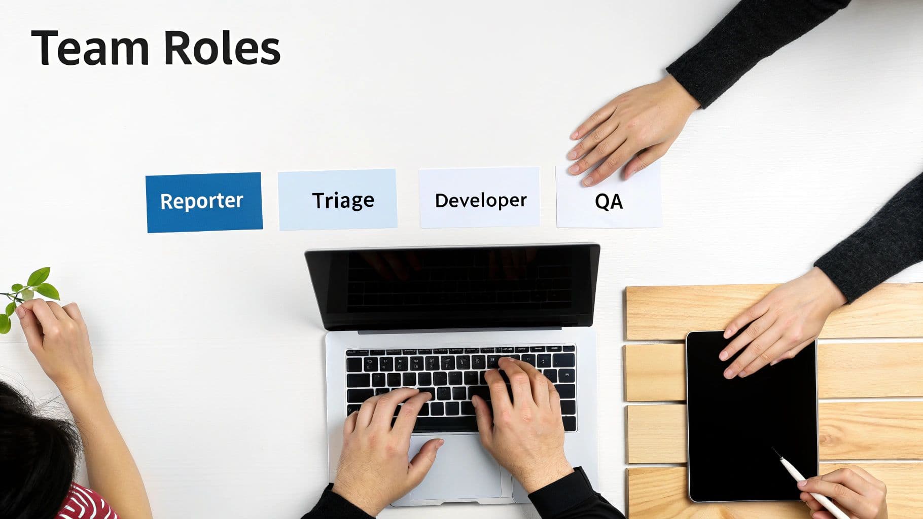 Overhead shot of a team desk with cards representing Reporter, Triage, Developer, and QA roles.
